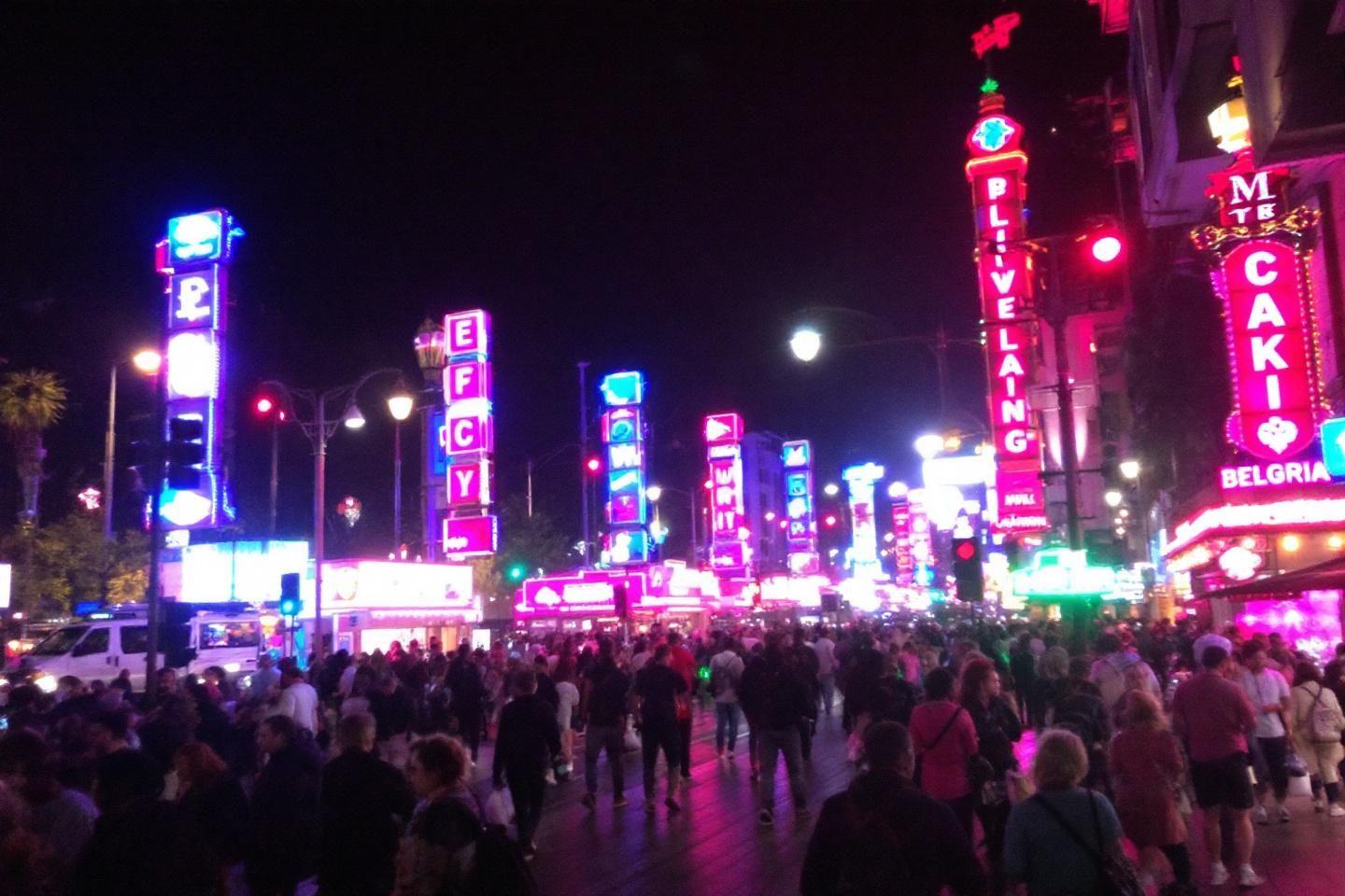 Rue animée de nuit avec lumières néon et grande affluence