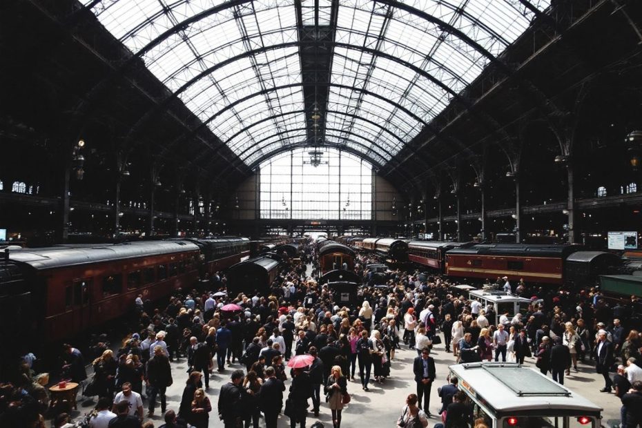 Foule massive dans une grande gare à verrière gothique