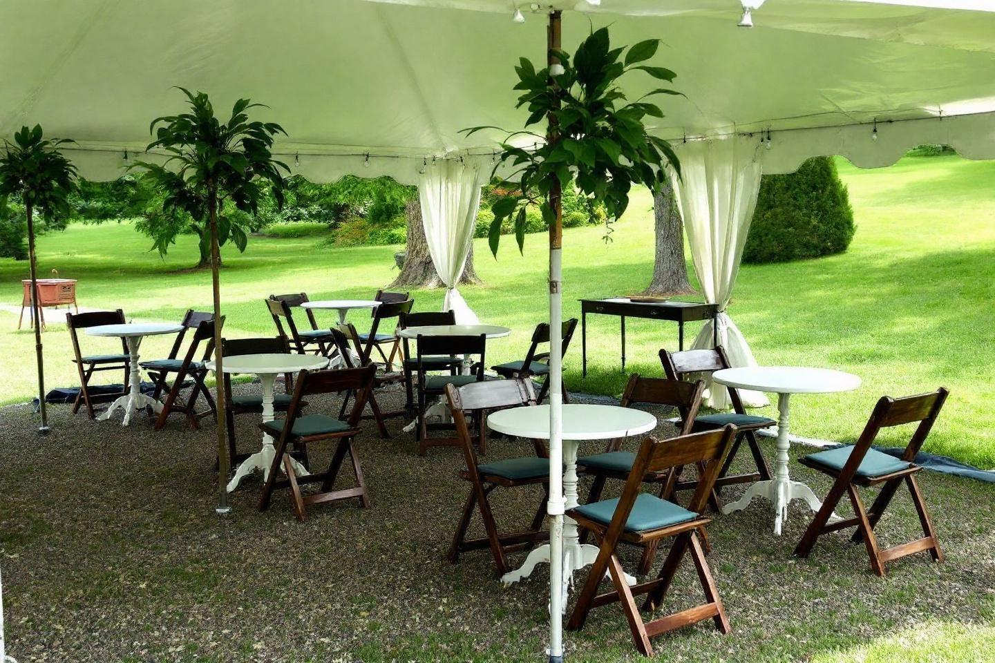 Tables et chaises pliantes sous une tente blanche dans un jardin