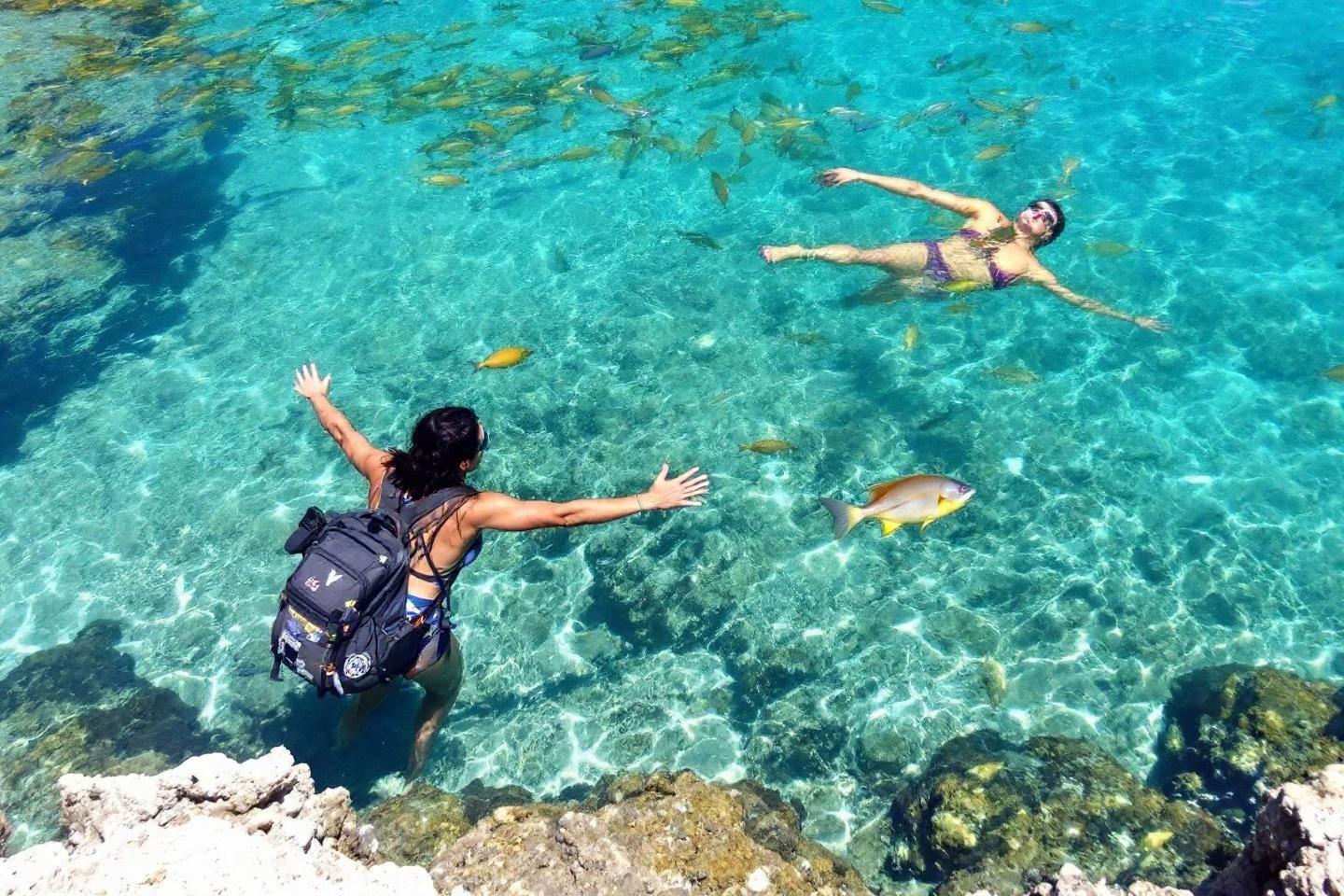 Deux personnes nagent près de rochers dans une mer cristalline