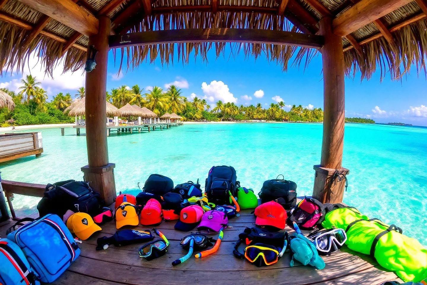 Masques et sacs colorés dans un bungalow sur pilotis turquoise